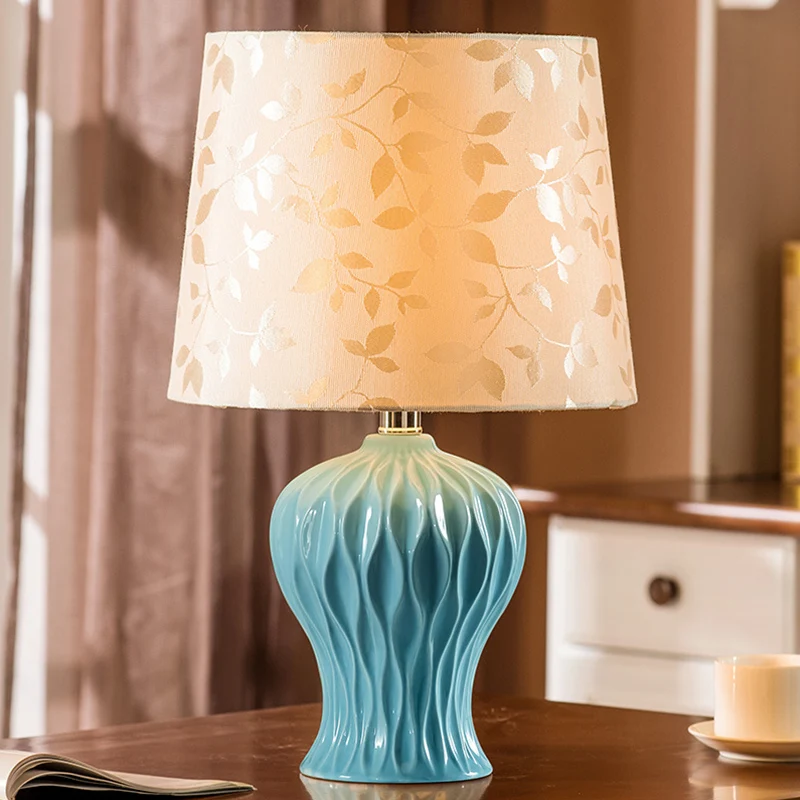 Met bladeren bedrukte stof Beige nachtlampje met tonvormige kap Traditionele tafelverlichting met 1 licht en blauwe urnbas...